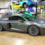 A grey Audi R8 parked in a garage, awaiting transport by an exotic car shipping company.