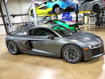 a grey audi r8 parked in a garage, awaiting transport by an exotic car shipping company.