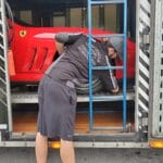 A man loading an exotic car into a truck for auto transport.